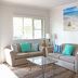 Cairns Beach Resort in Holloways Beach living room with sofas, glass coffee table and beach artwork