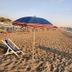 Hotel Cristina in Diamante: sandy beach with striped umbrella, lounge chair, and sea view