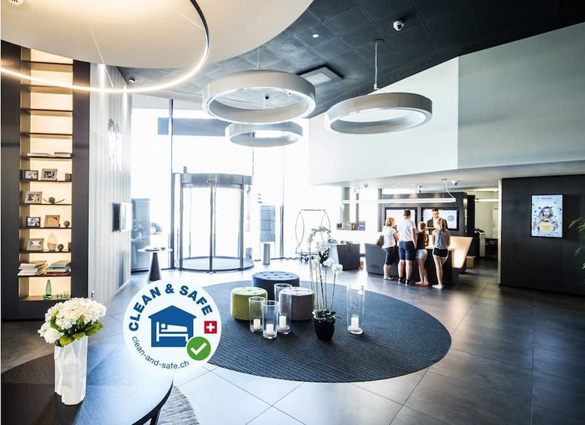 Novotel Basel City lobby with front desk, modern seating, and large circular ceiling lights in Basel