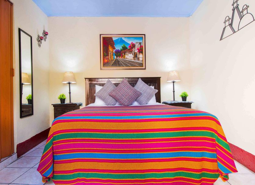 Hostal Antigua bedroom with colorful striped bedspread, twin lamps and wall art in Antigua