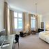 Hotel Kaiserhof Lübeck guest room with twin beds, seating area, TV, and tall windows