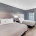 Quality Inn Laurinburg room with two beds, gray walls, window, and bedside lamp in Laurinburg