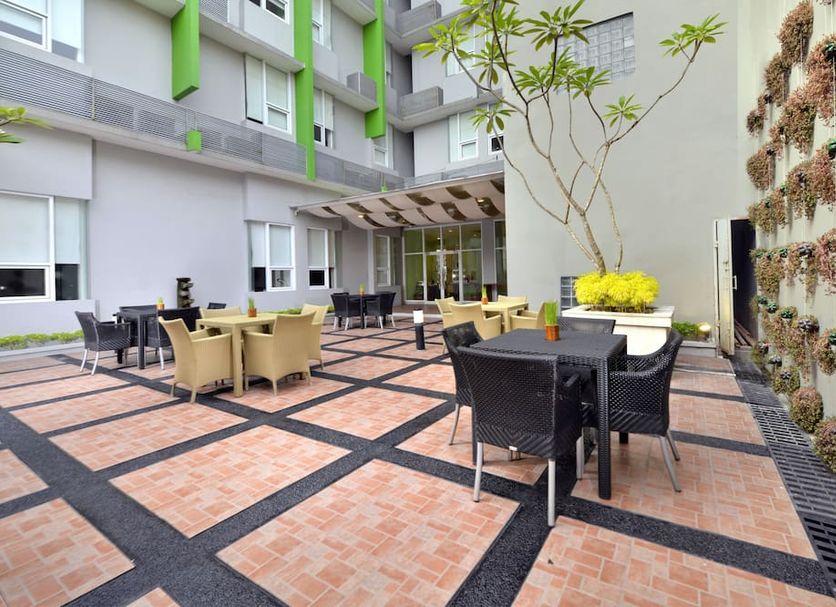 Whiz Hotel Malioboro Yogyakarta courtyard seating area in Yogyakarta with outdoor tables and wall planters