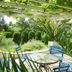 Albergo Giardino in Balatongyörök with a garden patio, round table, blue chairs, and pergola