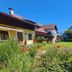 Pension Göschlberger in Mondsee with a garden, lawn, flowers, and a children’s slide under blue sky
