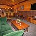 The Lodges at Cresthaven in Lake George cabin-style lounge with green sofa, coffee table, bar stools and TV