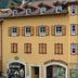 Borcanela Apartments in Moena, a yellow alpine building with shuttered windows and shopfronts