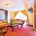Rainbow Ruiru Resort Nairobi lounge with wooden seating, coffee table, TV and bright window drapes