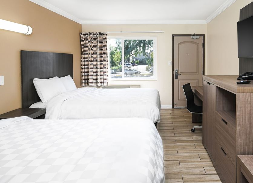 Sea Rock Inn - Long Beach guest room with two beds, desk, wall TV and window view