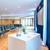 The Relais Cooden Beach in Bexhill-on-Sea conference room with rows of blue chairs and a presentation table