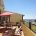 Gîte Au Coin De La Berge in Perce: ocean-view deck with patio seating and red umbrella