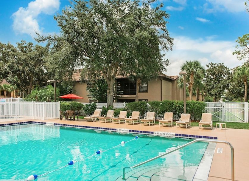 Alhambra Villas in Poinciana with an outdoor pool, curved steps, and lounge chairs under a blue sky
