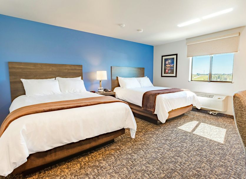 My Place Hotel-Idaho Falls room with two beds, blue accent wall, and window view in Idaho Falls