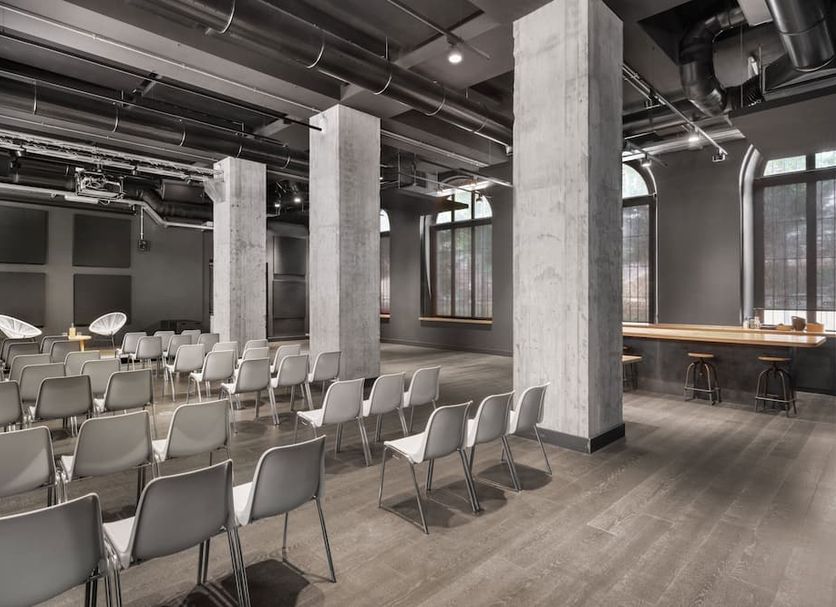 Combo Torino in Turin meeting room with rows of chairs, tall concrete columns, and large windows