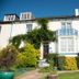 The Parks Guest House in Minehead, a white guest house with ivy, blue balcony, and landscaped garden