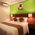 Guijo Suites Makati room in Makati with bed, bedside lamps, green accent wall and air conditioner