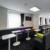 Sozo Hotel Nantes lounge with black sofas, white tables, colorful stools, wall TV and mirror