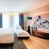 NYX Hotel Munich By Leonardo Hotels room with king bed, chaise lounge and leopard mural in Munich
