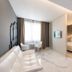 Hotel Milano Castello in Milan: modern suite with white sofa, small dining table, and bedroom area with glass door