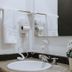 Travelers Orange Suites in Medellín bathroom sink with wall-mounted hair dryers, towels, and flowers
