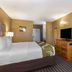 Quality Inn & Suites Westminster Seal Beach guest room with king bed, TV, desk and dresser in Westminster