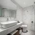 Lera Hotel Guangzhou bathroom with marble-style walls, vessel sink, toilet, and glass shower