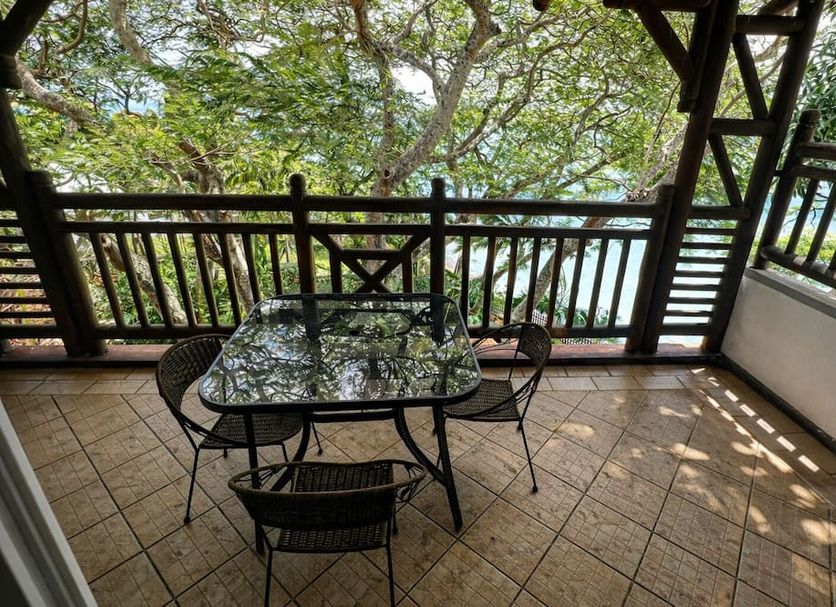 Oceanic Villa, Grand Baie: shaded balcony with table and chairs overlooking trees