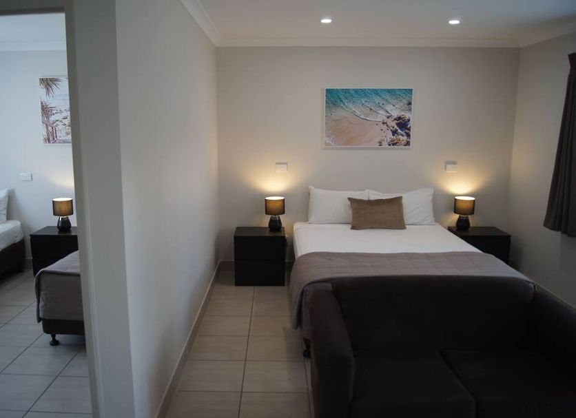 Beachside Motor Inn in Hervey Bay with a guest room featuring a bed, bedside lamps, and wall art