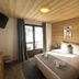 Le Cairn, Les Deux-Alpes: cozy wood-paneled bedroom with a double bed and balcony door