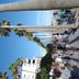 Pension Aduar in Marbella with palm-lined promenade and people walking by white buildings