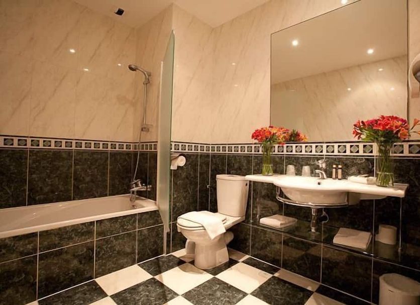 Hostellerie Les Hauts De Sainte Maure bathroom with bathtub, sink, toilet, and black-and-white tiled floor