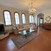 Hotel Villa Tiziana lounge with chandelier, arched windows, sofa, glass coffee table and tiled floor in Marina di Massa