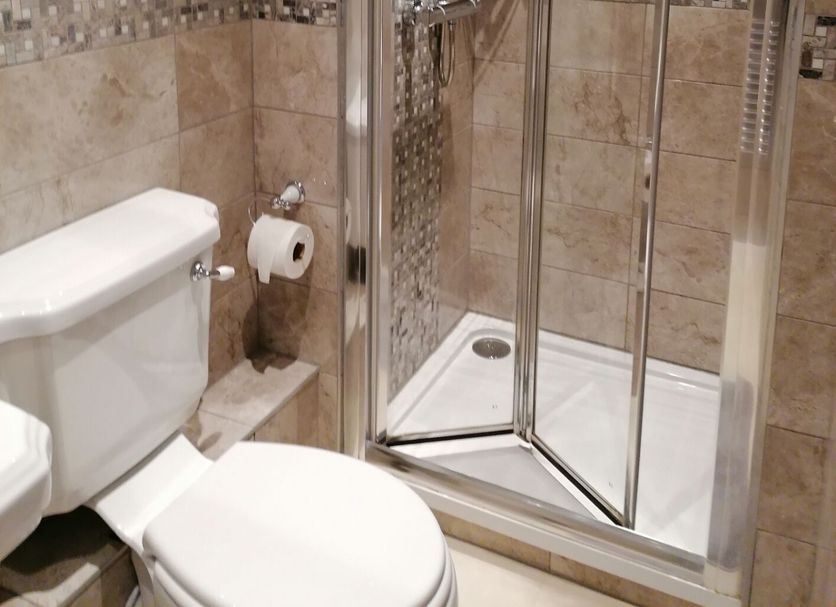 Edendale House bathroom with glass corner shower, toilet and tiled walls in Southport