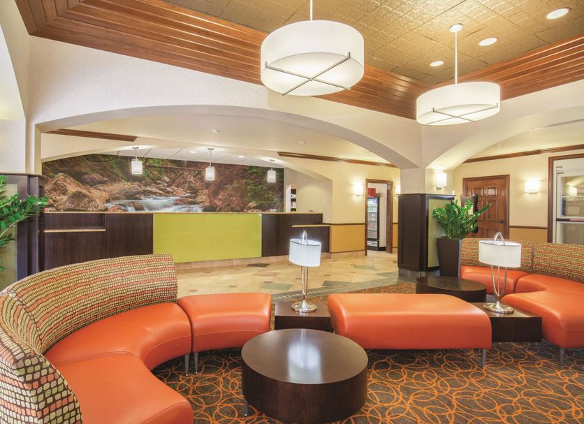 La Quinta Inn & Suites by Wyndham Bentonville lobby with orange sectional seating and wood ceiling