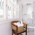 Eveline Portosole Hotel San Remo bathroom with glass shower, wicker chair and striped window awning