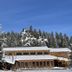 The Lodge at Lolo Hot Springs in Lolo, snow-covered lodge with tall pine trees and blue sky