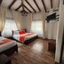 Hotel Gran Sirius in Sachica: guest room with two beds, wood ceiling beams, TV, and bathroom