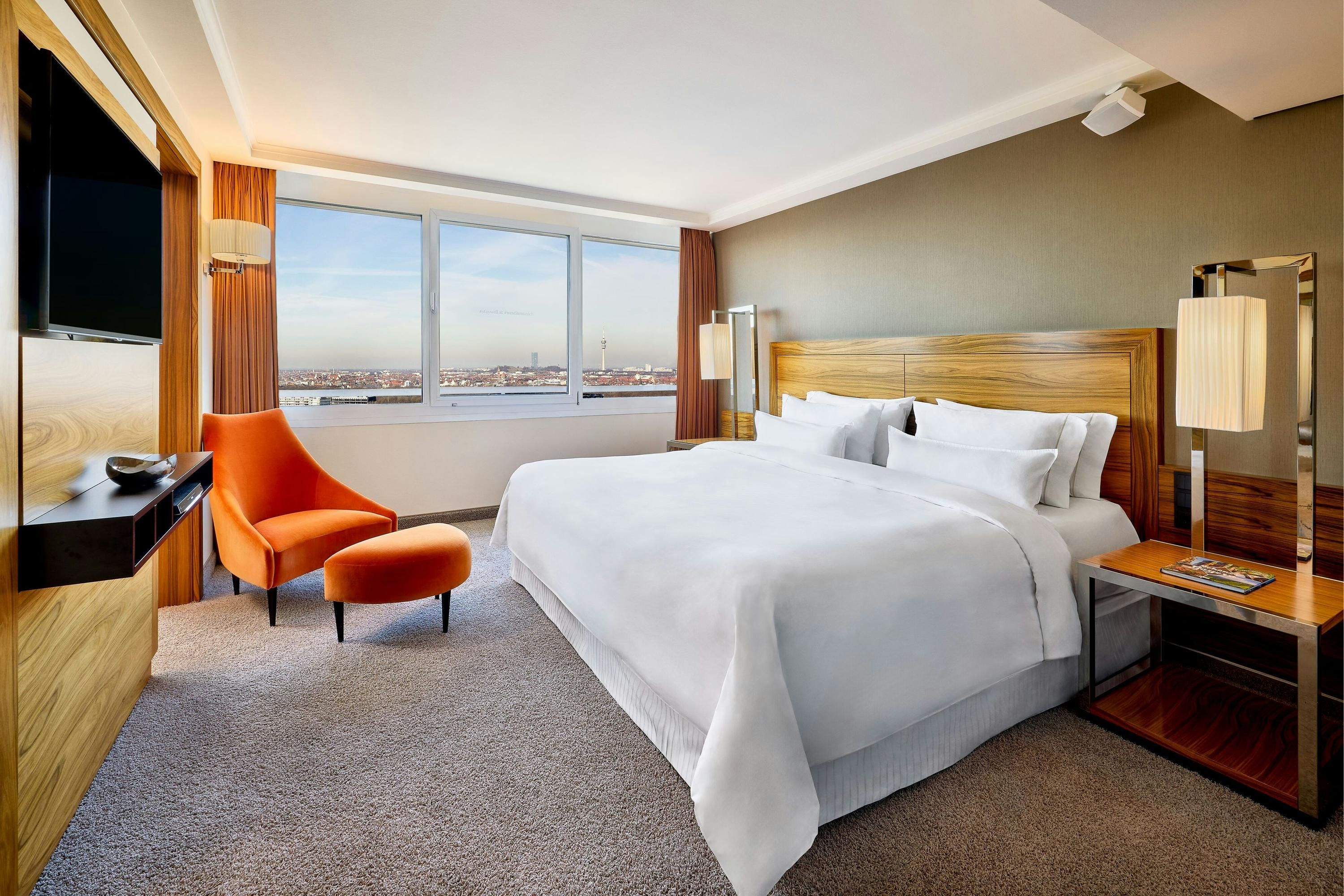 The Westin Grand Munich room with king bed, orange chair and city view in Munich