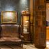 Hotel de la Ville Monza lounge with leather armchair, display cabinets and framed art in Monza