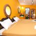 La Villa Creole in Pondicherry room with carved wood bed, bright yellow walls and colorful door