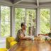 The Stavrand Russian River Valley in Guerneville: guests share tea at a table beside tall forest-view windows.