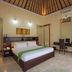 O Villas Seminyak bedroom with king bed, desk, chair, and vaulted wood ceiling in Kuta