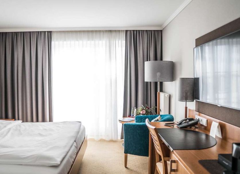 Klostermaier Hotel & Restaurant room in Icking with bed, desk, chair, and large window with curtains