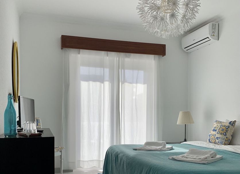 Manelisa Cascais guest room with twin beds, sheer curtains, and a wall-mounted air conditioner