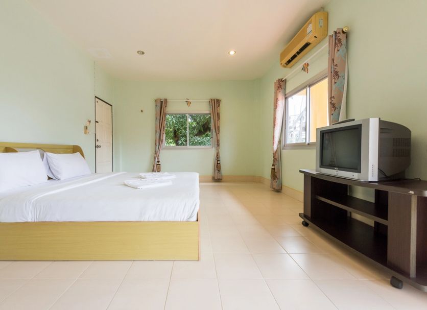 Pachumas Mansion in Karon guest room with bed, TV stand, tiled floor and window view