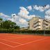 Tennis court at Una Hotels Forte Dei Marmi in Forte dei Marmi with hotel buildings and blue sky