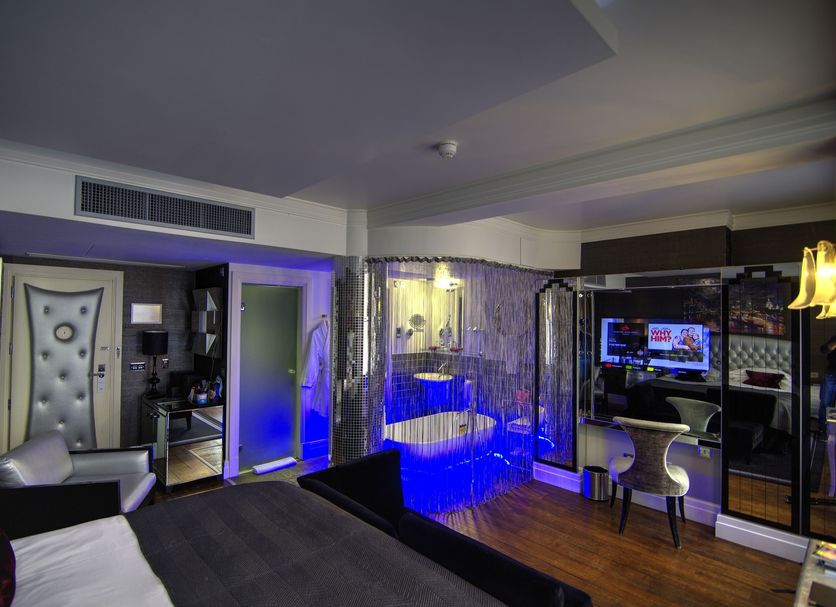 Karma Sanctum Soho Hotel, London: stylish suite with circular blue-lit soaking tub and seating area