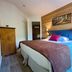 Résidence Côté Chalet in Thonon-les-Bains: cozy bedroom with wood-paneled wall, bed, and bedside lamps