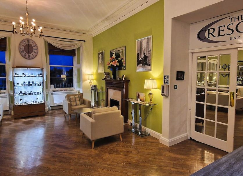 The Osborne Hotel in Torquay lounge with chairs, fireplace, bar entrance and windows at dusk