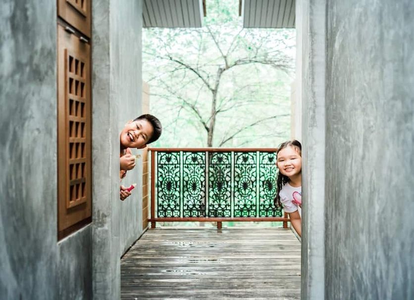 House Of Passion Amphawa balcony with two children peeking out over a wooden walkway in Amphawa